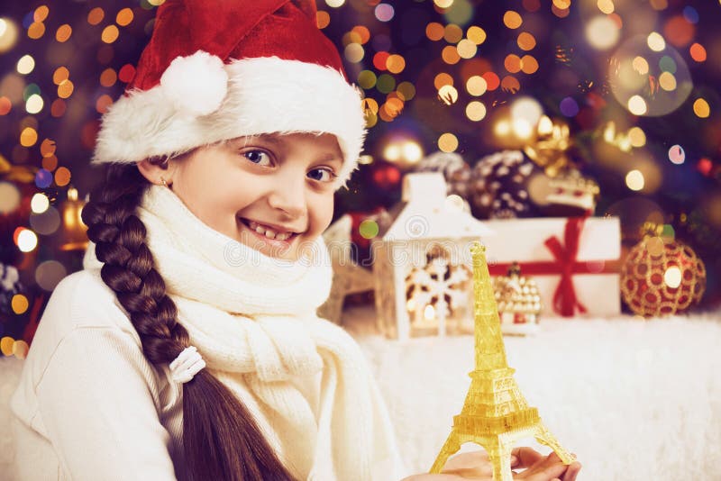 L'enfant de fille posant avec la décoration de jouet et de Noël de Tour Eiffel sur le fond foncé, les lumières lumineuses et le b images stock L'enfant de fille posant avec la décoration de jouet et de Noël de Tour Eiffel sur le fond foncé, les lumières lumineuses et le b images stock