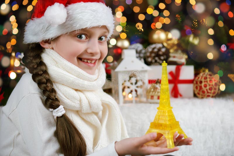 L'enfant de fille s'est habillé dans le chapeau de Santa avec le jouet de Tour Eiffel et les cadeaux de Noël sur l'obscurité ont photo stock L'enfant de fille s'est habillé dans le chapeau de Santa avec le jouet de Tour Eiffel et les cadeaux de Noël sur l'obscurité ont photo stock