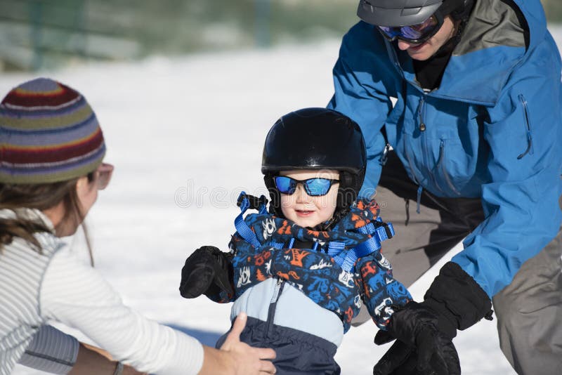 L'enfant en bas âge apprend à skier avec le papa tandis que des montres de maman Habillé sans risque images libres de droits L'enfant en bas âge apprend à skier avec le papa tandis que des montres de maman Habillé sans risque images libres de droits