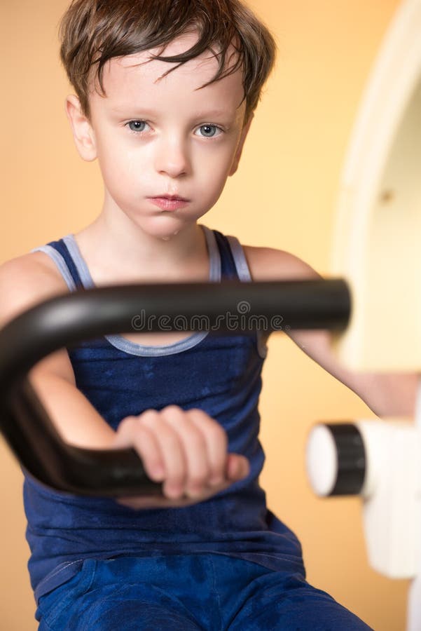 L'enfant est formé sur un vélo stationnaire Style de vie sain images libres de droits L'enfant est formé sur un vélo stationnaire Style de vie sain images libres de droits