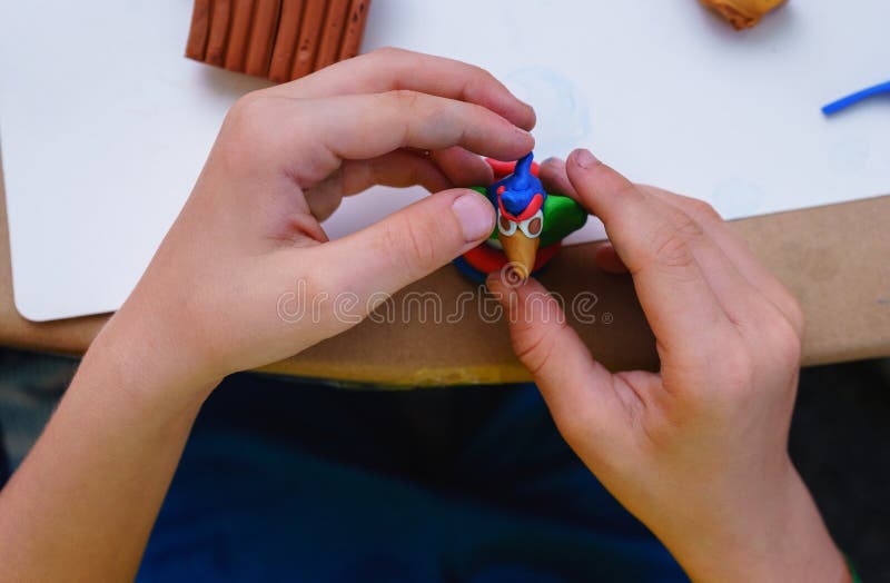 L'enfant est occupé à modeler de la pâte à modeler se reposant dans la table du ` s d'enfants photo stock L'enfant est occupé à modeler de la pâte à modeler se reposant dans la table du ` s d'enfants photo stock