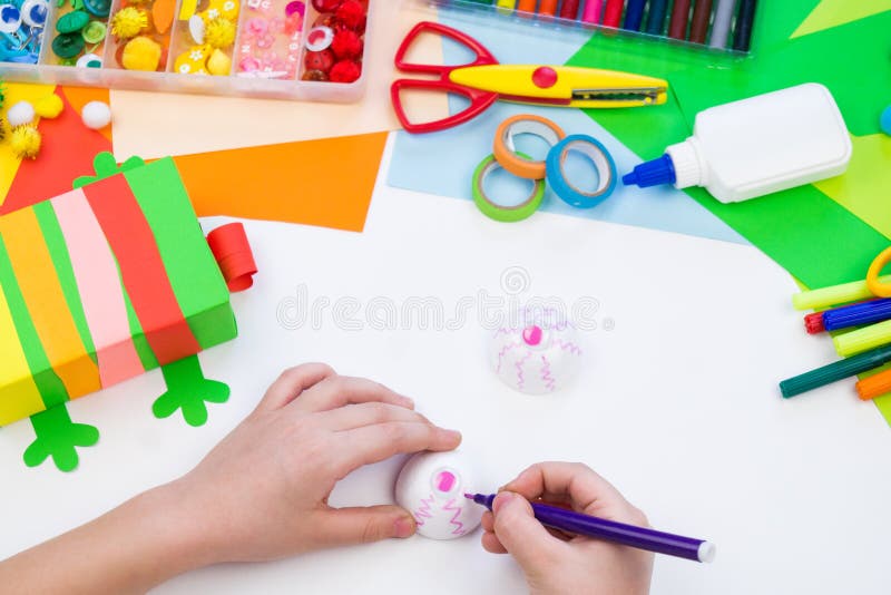 Child makes a hack box chameleon. Material for creativity on a white background. Baby hand. Rainbow colored paper. Child makes a hack box chameleon. Material for creativity on a white background. Baby hand. Rainbow colored paper