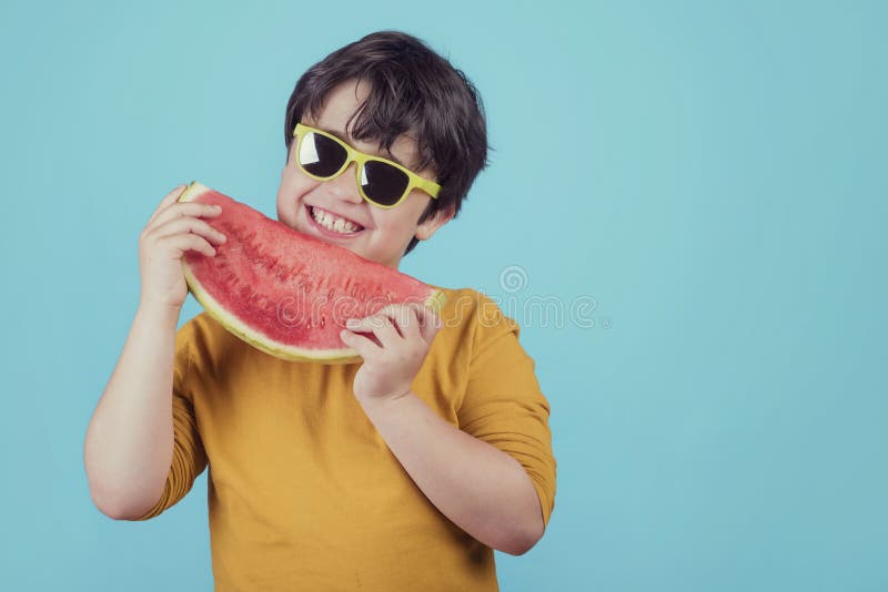 L'enfant heureux avec des lunettes de soleil mange la pastèque images libres de droits L'enfant heureux avec des lunettes de soleil mange la pastèque images libres de droits