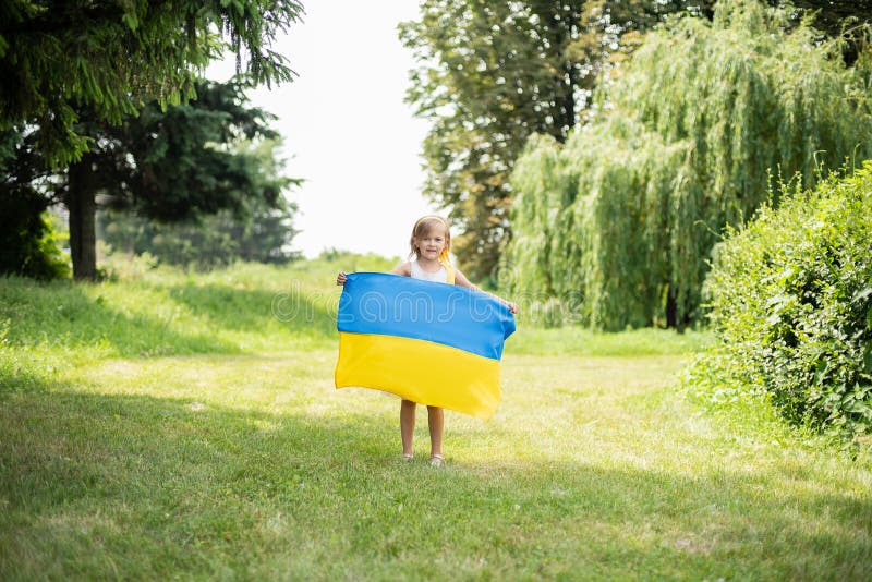 L'enfant porte le flottement drapeau bleu et jaune de l'Ukraine dans le domaine Jour de la D?claration d'Ind?pendance du ` s de l photos libres de droits L'enfant porte le flottement drapeau bleu et jaune de l'Ukraine dans le domaine Jour de la D?claration d'Ind?pendance du ` s de l photos libres de droits
