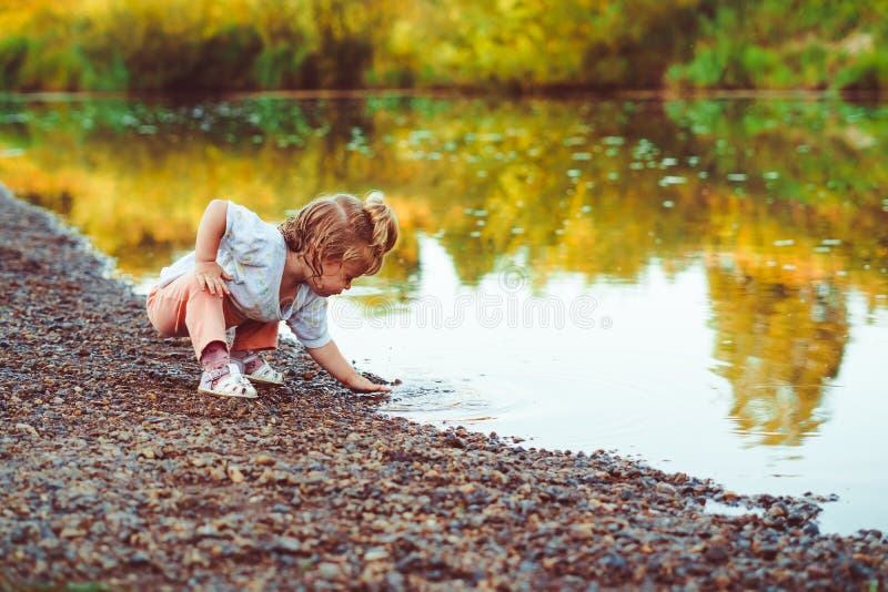 L'enfant se tient prêt la rivière photo libre de droits L'enfant se tient prêt la rivière photo libre de droits