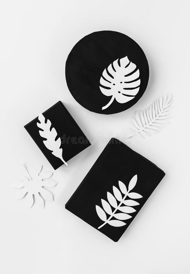 L'ensemble scandinave noir de cadeau de style avec le papier tropical blanc part photographie stock libre de droits L'ensemble scandinave noir de cadeau de style avec le papier tropical blanc part photographie stock libre de droits