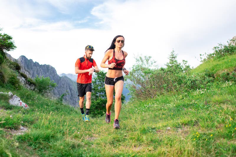 L'entraîneur sportif mesure la période d'une femme féminine de course d'athlète dans la montagne image stock L'entraîneur sportif mesure la période d'une femme féminine de course d'athlète dans la montagne image stock