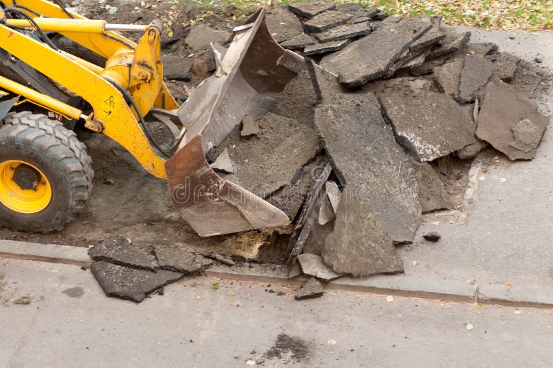 Excavator removes the old asphalt covering on the city street. Excavator removes the old asphalt covering on the city street