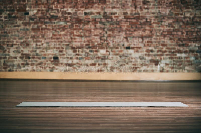 L'espace vide au centre de fitness, mur de briques, plancher en bois naturel, studio moderne de grenier, tapis déroulé de yoga su photo stock L'espace vide au centre de fitness, mur de briques, plancher en bois naturel, studio moderne de grenier, tapis déroulé de yoga su photo stock