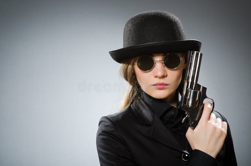 L'espion féminin avec l'arme contre le gris photographie stock libre de droits