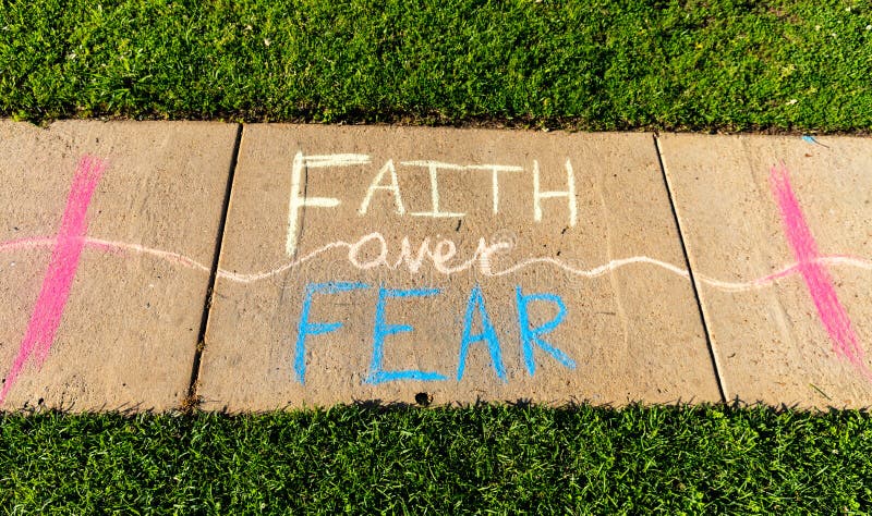 L'espressione 'fede sulla paura' scritta con gesso sul marciapiede su fondo pavimentazione in calcestruzzo grigio