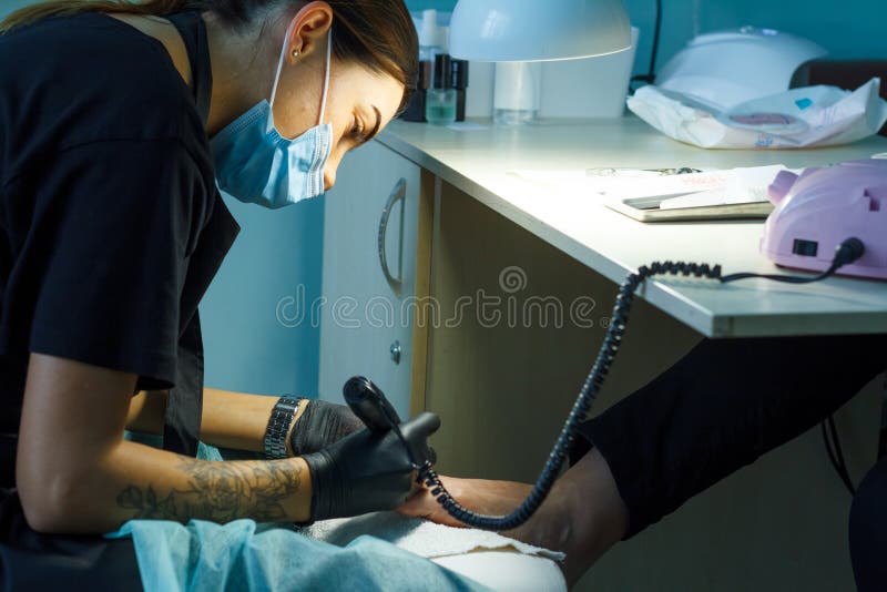 L'estetista frantuma la barra cava chiodi per un pedicure nel salone di bellezza fotografia stock libera da diritti L'estetista frantuma la barra cava chiodi per un pedicure nel salone di bellezza fotografia stock libera da diritti