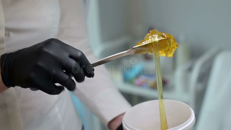 L'estetista prende la pasta dello zucchero dal barattolo