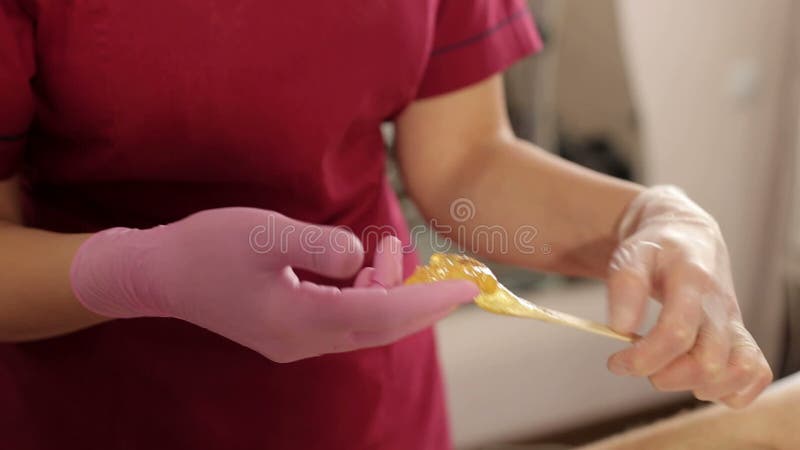 L'estetista prende la pasta dello zucchero dalle banche per la depilazione del seno maschio