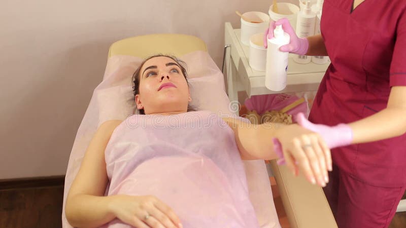 L'estetista spruzza la polvere di talco sulla mano di una ragazza prima della depilazione