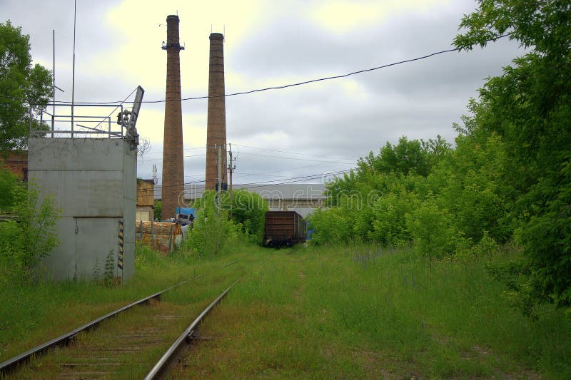 L'extrémité d'une ligne ferroviaire abandonnée de vieux voitures et tuyaux d'une usine abandonnée Landdscape image libre de droits L'extrémité d'une ligne ferroviaire abandonnée de vieux voitures et tuyaux d'une usine abandonnée Landdscape image libre de droits