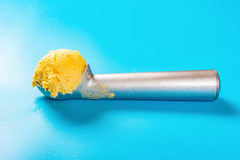 L?ffel mit Mangoaroma-Eiscremeball auf blauem Hintergrund lizenzfreies stockfoto L?ffel mit Mangoaroma-Eiscremeball auf blauem Hintergrund lizenzfreies stockfoto