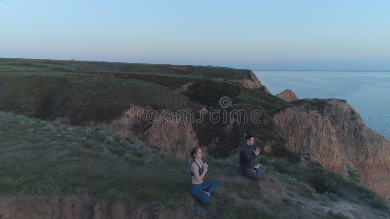 L'harmonie spirituelle, le couple de yogi en position lotus méditent pendant le yoga dans la nature assis sur le versant près de