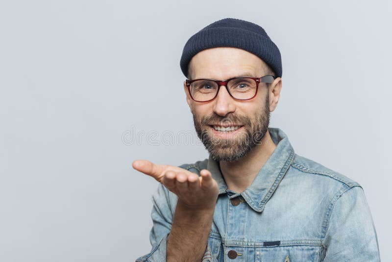 L'heureux mâle barbu dans l'eyewear à la mode exprime son amour, montre l'AI photos stock L'heureux mâle barbu dans l'eyewear à la mode exprime son amour, montre l'AI photos stock