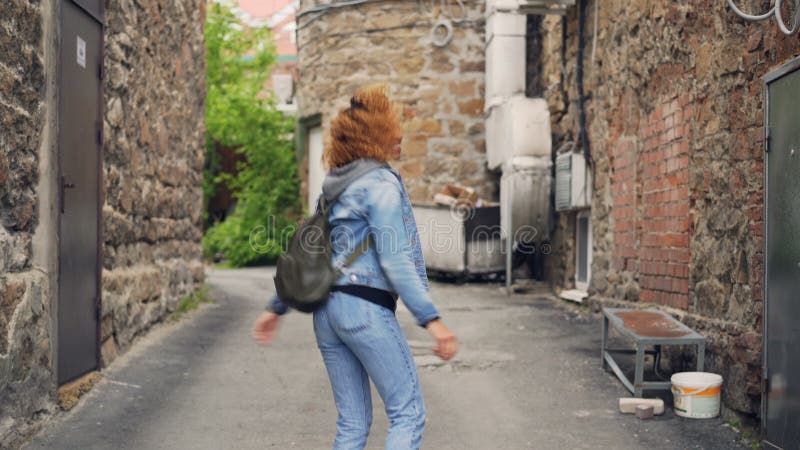 L'heureux touriste de fille heureuse d'Afro-américain avec le sac à dos est marchant et dansant dans la rue avec les murs en pier banque de vidéos