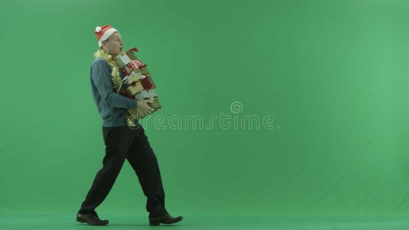 L'homme adulte marche avec la pile des cadeaux de Noël, fond vert de clé de chroma