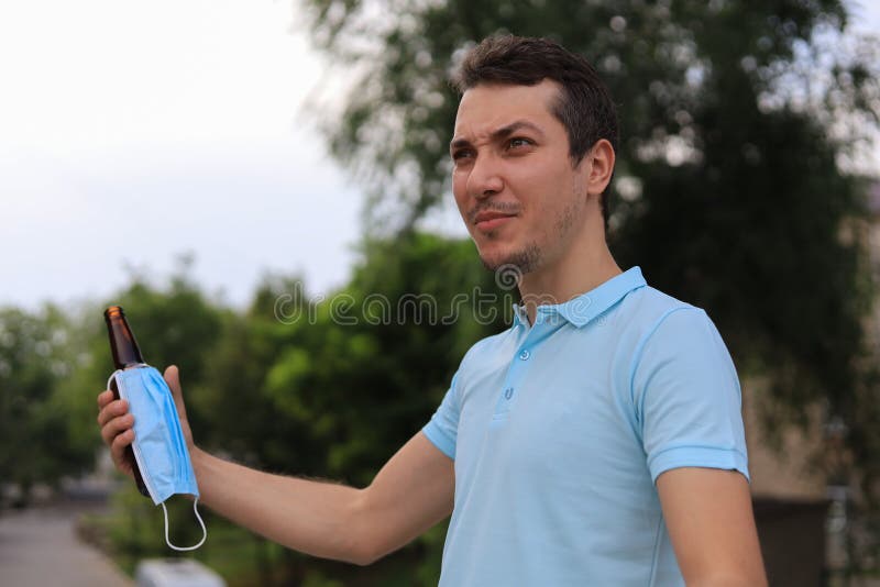 A cunning young man enjoys drinking an alcoholic drink in the city using life hack. A mask dressed on a bottle does not formally violate the law. A cunning young man enjoys drinking an alcoholic drink in the city using life hack. A mask dressed on a bottle does not formally violate the law.