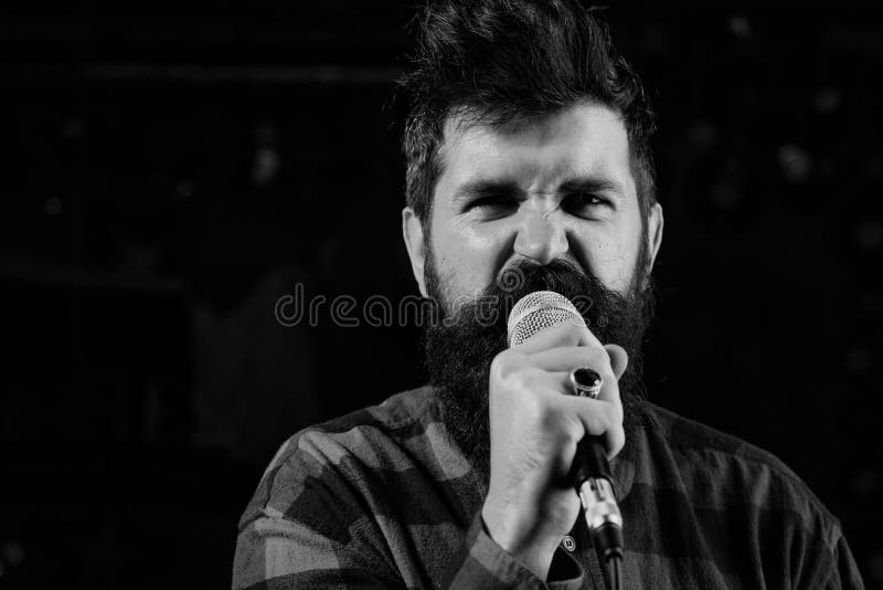 L'homme avec le visage enthousiaste tient le microphone, chanson de chant, fond noir images libres de droits L'homme avec le visage enthousiaste tient le microphone, chanson de chant, fond noir images libres de droits