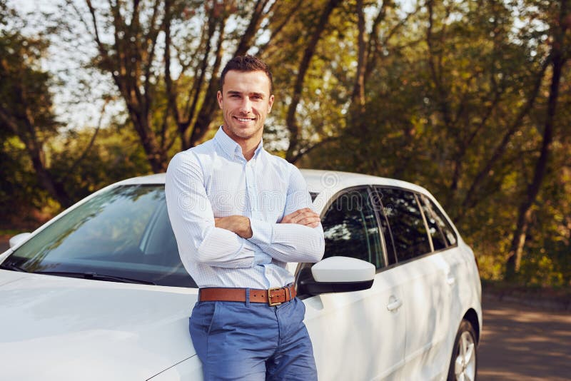 L'homme avec les bras croisés se tient devant sa nouvelle voiture photographie stock libre de droits L'homme avec les bras croisés se tient devant sa nouvelle voiture photographie stock libre de droits