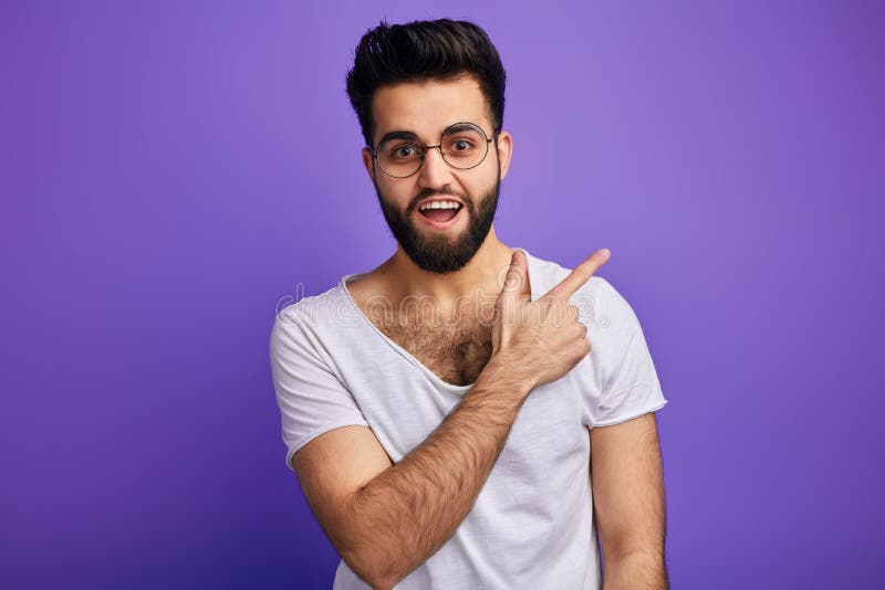 L'homme barbu heureux gai indique heureusement à quelque part photographie stock L'homme barbu heureux gai indique heureusement à quelque part photographie stock