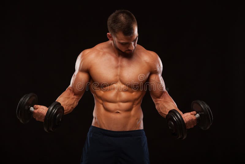 L'homme bel musculaire s'exerce avec des haltères dans le gymnase D'isolement sur le fond noir avec Copyspace photo libre de droits L'homme bel musculaire s'exerce avec des haltères dans le gymnase D'isolement sur le fond noir avec Copyspace photo libre de droits