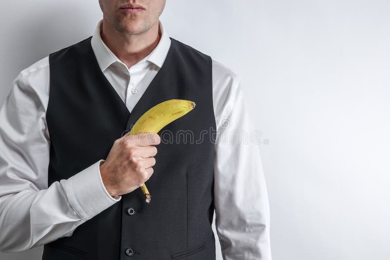 L'homme bien habillé tenant une banane aiment une arme à feu photo stock L'homme bien habillé tenant une banane aiment une arme à feu photo stock