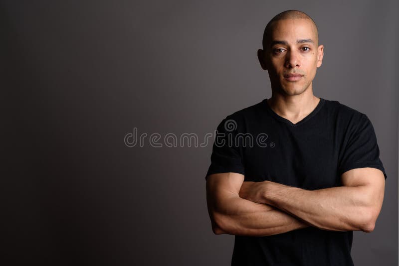 L'homme chauve bel utilisant la chemise noire avec des bras a croisé photo libre de droits L'homme chauve bel utilisant la chemise noire avec des bras a croisé photo libre de droits