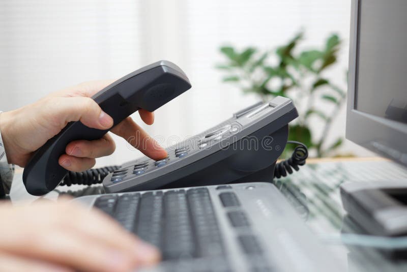 L'homme d'affaires compose un numéro de téléphone dans le bureau photo stock L'homme d'affaires compose un numéro de téléphone dans le bureau photo stock