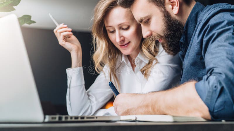 L'homme d'affaires et la femme d'affaires s'asseyent à la table devant l'ordinateur portable, discutant le concept d'affaires L'h photo stock L'homme d'affaires et la femme d'affaires s'asseyent à la table devant l'ordinateur portable, discutant le concept d'affaires L'h photo stock