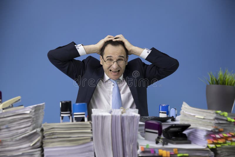 Feeling tired and overworked businessman grabbed his head depressed in business stress at office desk loaded of. Feeling tired and overworked businessman grabbed his head depressed in business stress at office desk loaded of
