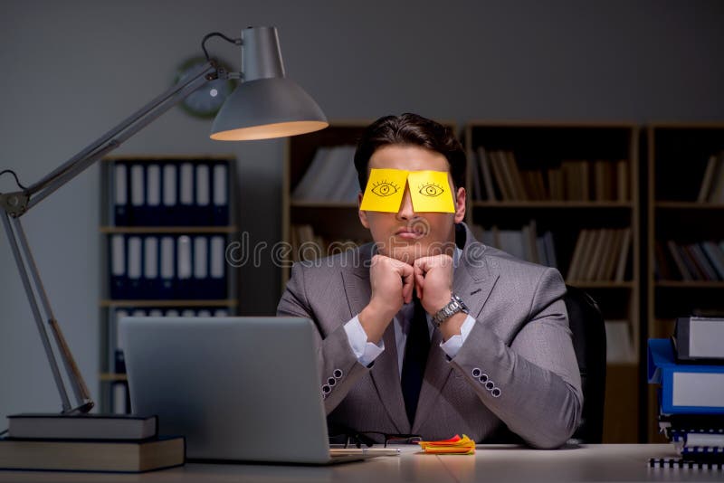 L'homme d'affaires restant tard pour trier des priorités image libre de droits L'homme d'affaires restant tard pour trier des priorités image libre de droits