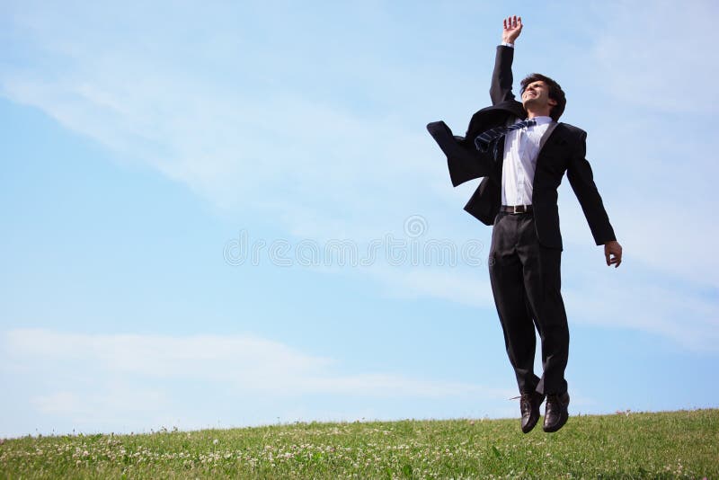 L'homme d'affaires sautant sur l'herbe images stock L'homme d'affaires sautant sur l'herbe images stock