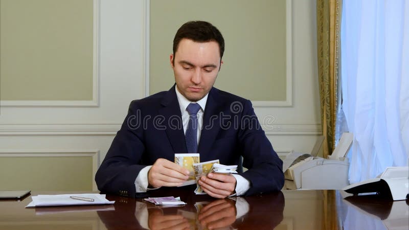 L'homme d'affaires sûr compte l'argent et des notes de fabrication photo libre de droits L'homme d'affaires sûr compte l'argent et des notes de fabrication photo libre de droits