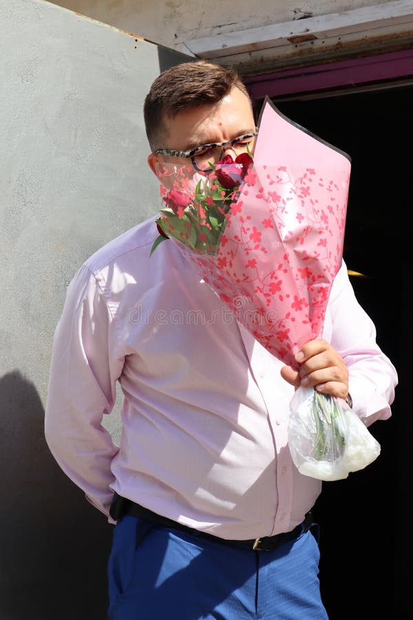 L'homme dans l'amour avec un grand bouquet des fleurs, parle avec son aimé au téléphone photographie stock libre de droits L'homme dans l'amour avec un grand bouquet des fleurs, parle avec son aimé au téléphone photographie stock libre de droits