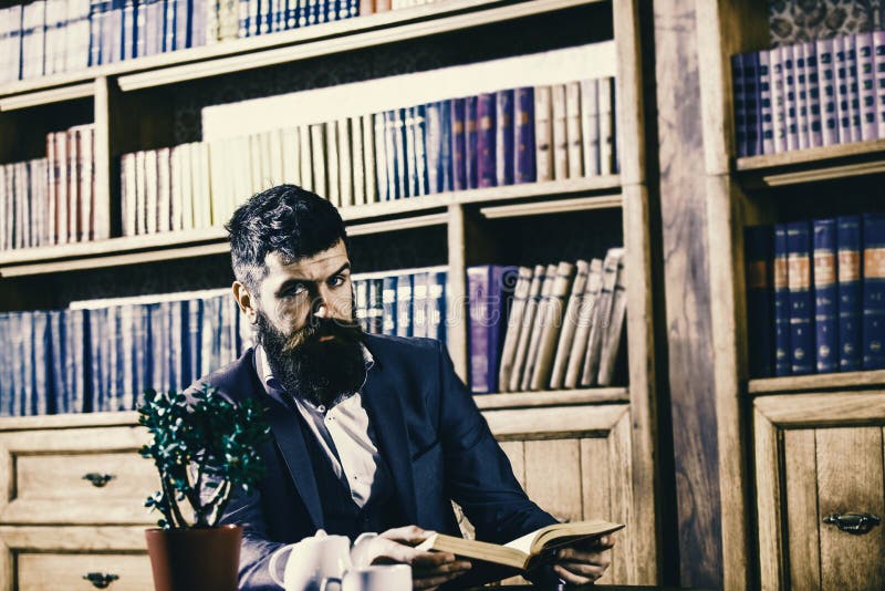 L'homme dans le costume classique s'assied dans l'intérieur de vintage, la bibliothèque, étagères à livres sur le fond Homme démo photographie stock L'homme dans le costume classique s'assied dans l'intérieur de vintage, la bibliothèque, étagères à livres sur le fond Homme démo photographie stock