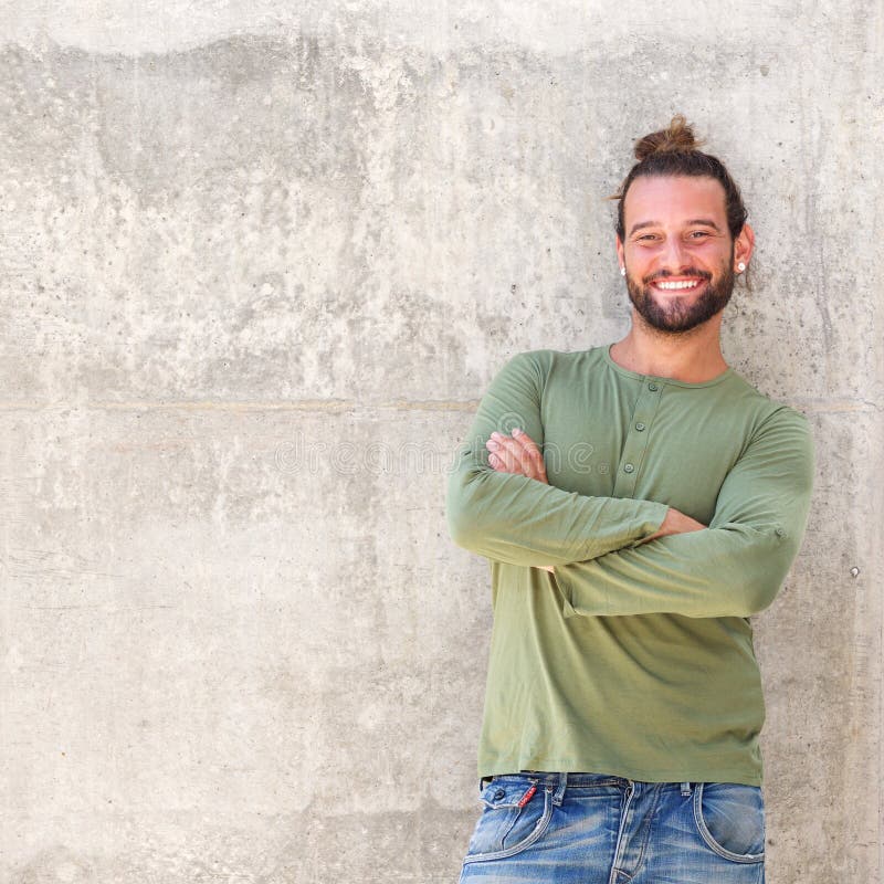 L'homme de sourire avec des bras a croisé le penchement contre le mur photo libre de droits L'homme de sourire avec des bras a croisé le penchement contre le mur photo libre de droits