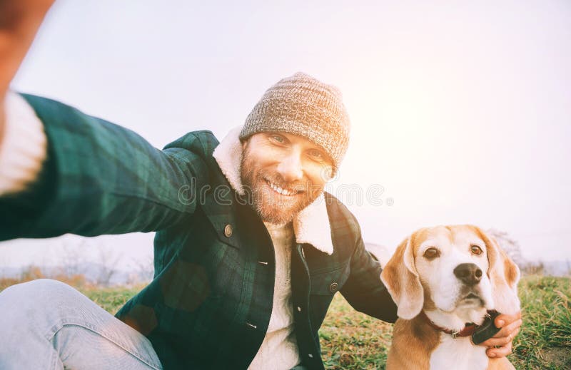 Cheerful smiling Man takes selfie photo with his best friend beagle dog during walking. Human and pets concept image. Cheerful smiling Man takes selfie photo with his best friend beagle dog during walking. Human and pets concept image
