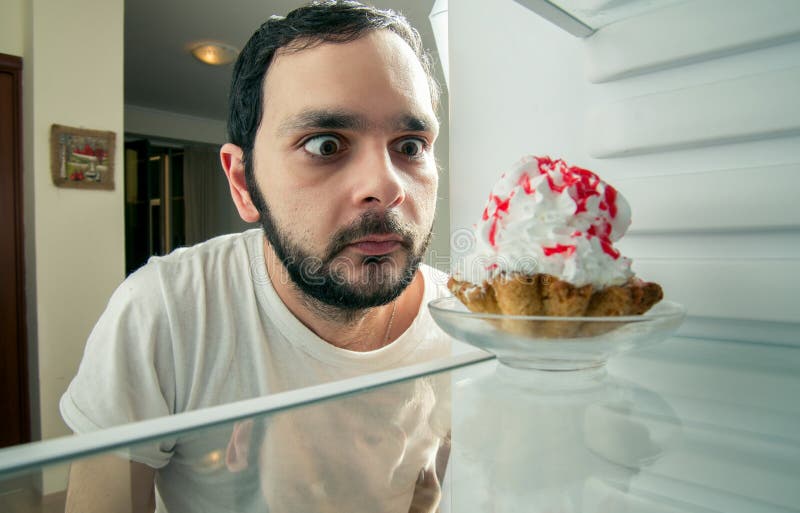 L'homme drôle voit le gâteau doux dans le réfrigérateur image libre de droits L'homme drôle voit le gâteau doux dans le réfrigérateur image libre de droits
