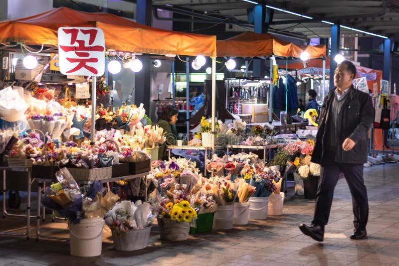 L'homme en passant par des fleurs calent la nuit. Marché en plein air. Homme de retour à la maison du travail ou d'un dîner avec d photo stock
