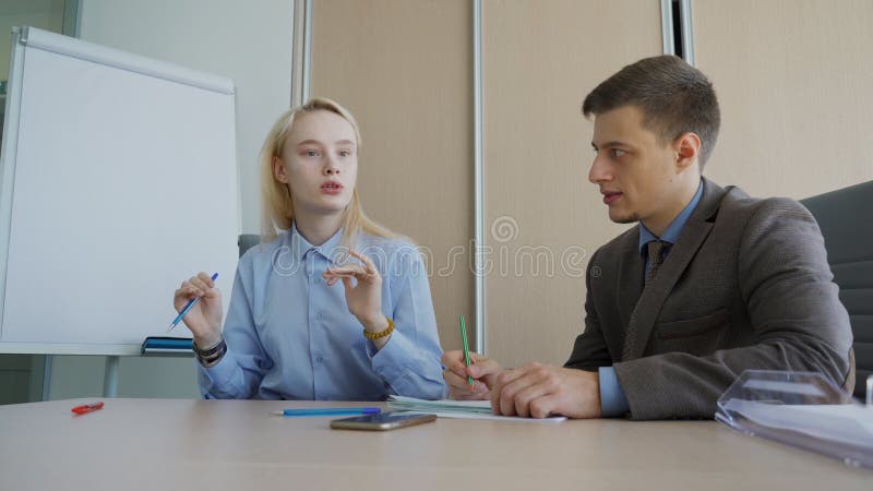 L'homme et la femme discutent travailler des questions, se reposant dans le bureau moderne