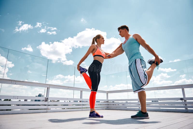 L'homme et la femme se soutiennent tout en s'exerçant dehors photo libre de droits L'homme et la femme se soutiennent tout en s'exerçant dehors photo libre de droits