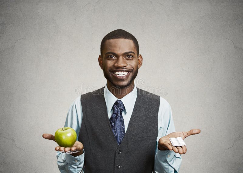 L'homme heureux d'affaires tient la pomme et les pilules vertes images libres de droits L'homme heureux d'affaires tient la pomme et les pilules vertes images libres de droits