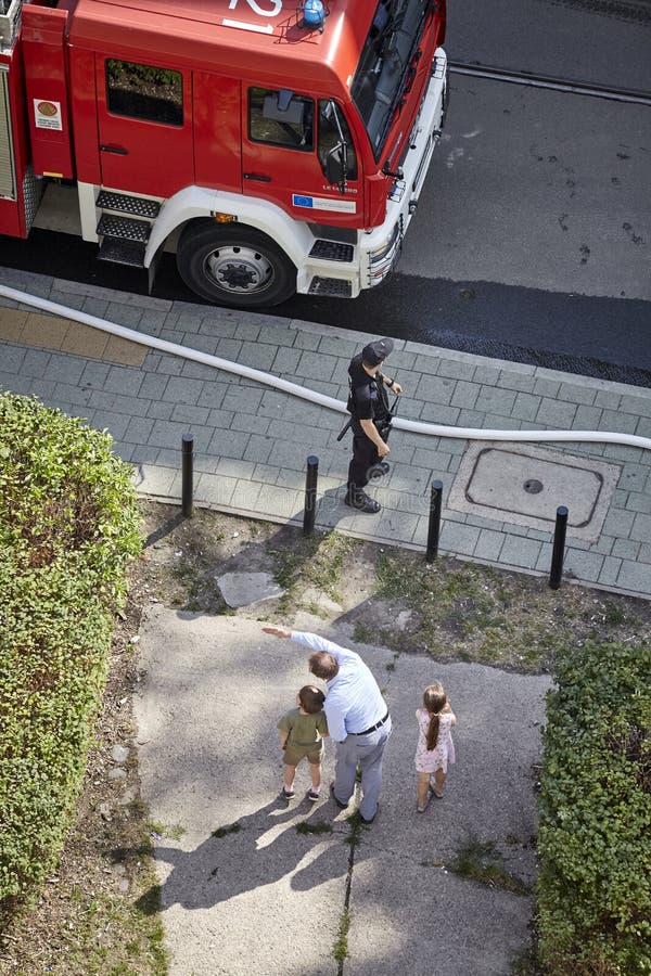L'homme montre à des enfants des sapeurs-pompiers qui disposent à s'éteindre le feu image stock L'homme montre à des enfants des sapeurs-pompiers qui disposent à s'éteindre le feu image stock