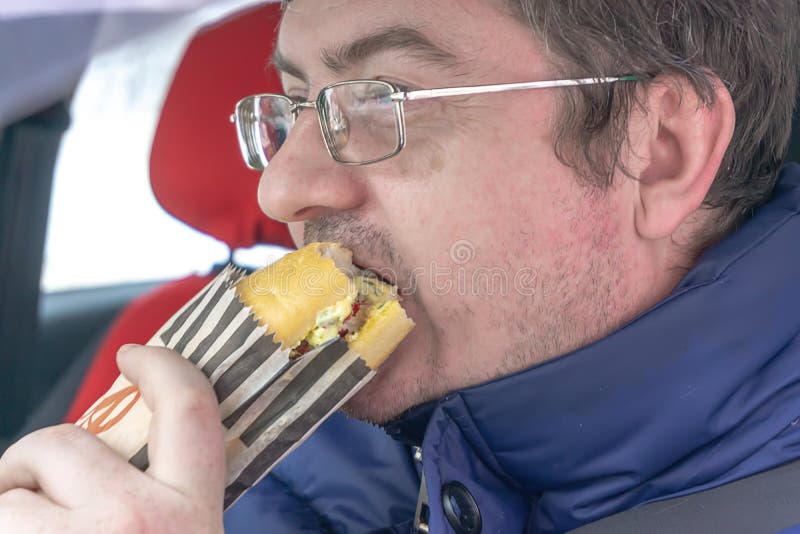 L'homme portant des lunettes mange le sandwich photographie stock L'homme portant des lunettes mange le sandwich photographie stock