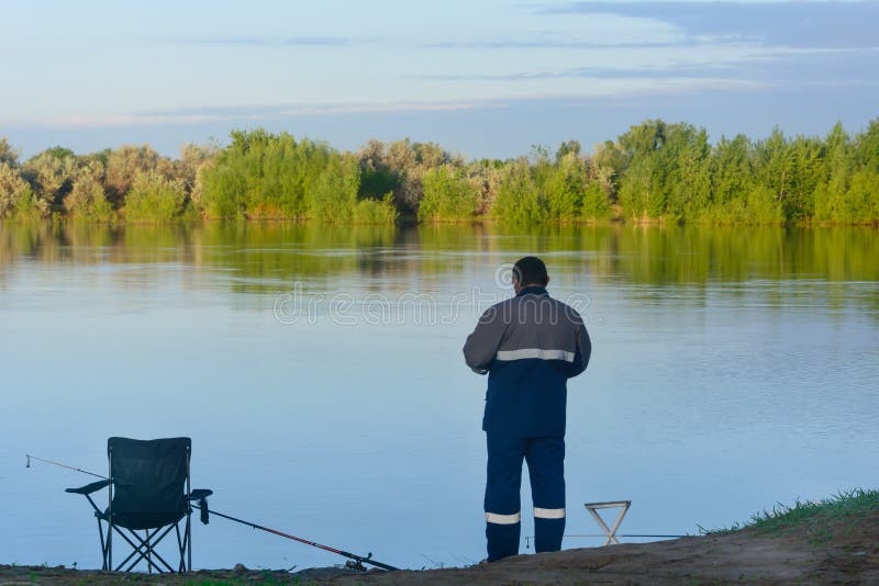 L'homme pêche sur la rivière avec la verge tôt le matin. arrière vue flou de focus sélectif photos libres de droits